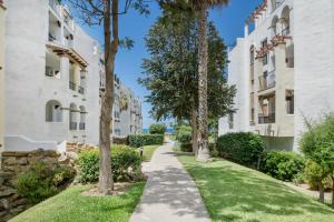a path between two buildings with trees and grass at Bella Vistas in Zahara de los Atunes