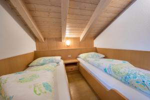 two beds in a small room with wooden ceilings at App Sonne Nr 20 in Lutago