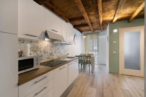 a kitchen with white cabinets and a dining room at Prima Del Cielo -Appartamento Monti in Esino Lario