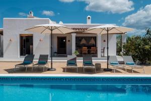 a villa with a swimming pool and chairs and umbrellas at Can Joan Durban in Sant Joan de Labritja