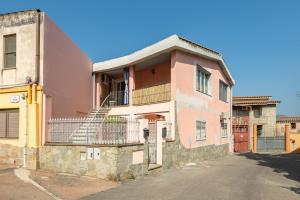 a pink house with a balcony on a street at Casa Vacanze 4 Venti in Muravera