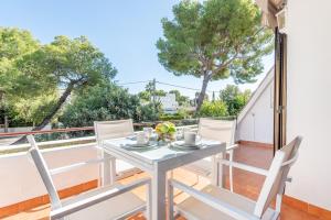 a white table and chairs on a balcony with trees at Mercuri in Port d'Alcudia