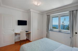 a bedroom with a bed and a desk and a window at Luxury Villa Seaview con jacuzzi in Conca dei Marini +31 photos
