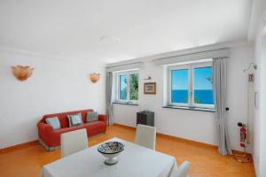 a living room with a table and a red couch at Luxury Villa Seaview con jacuzzi in Conca dei Marini