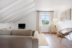 a white living room with a couch and a tv at Casa da Olides - Studio in Santana