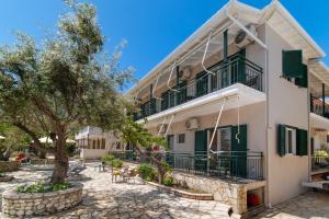 a large white building with green balconies and a tree at Nikiana Club - Studio 3 in Nikiana +14 photos