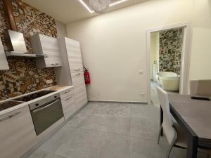 a kitchen with white cabinets and a table and a sink at Valepiace 1 in Piacenza +5 photos
