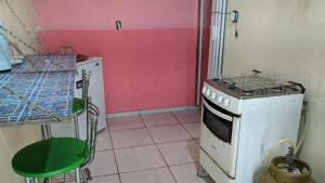 a kitchen with a stove and a pink wall at Kitinete e suite Recanto do Bem-te-vi in Serra