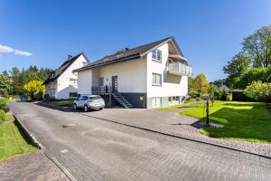 a white house with a car parked on the street at Ferienwohnung Urban in Bestwig