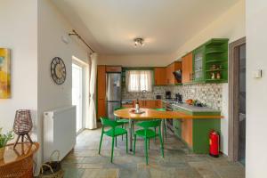 a kitchen with green cabinets and a table and chairs at Villa Melenia 2 in Agia Pelagia +25 photos