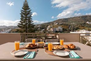 a table with plates of food and orange juice at Villa Melenia 2 in Agia Pelagia