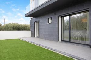 a black house with a yard of green grass at Apulia Apartment in Apúlia