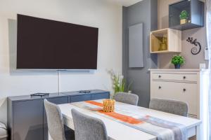 a dining room with a table and a flat screen tv at Le Mas de la Mer in Frontignan