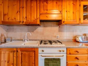 a kitchen with wooden cabinets and a white stove top oven at Chalet Baita Santina by Interhome in Peglio +23 photos