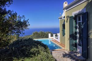 a house with a swimming pool and the ocean at Villa Ostria in Tsoukalades +8 photos