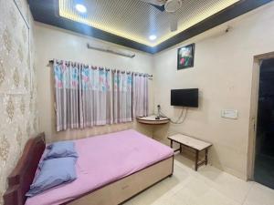 a bedroom with a bed and a desk and a tv at Hotel Shiv-Shakti in Solapur