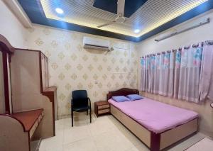 a small bedroom with a bed and a chair at Hotel Shiv-Shakti in Solapur +2 photos