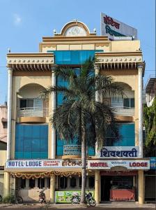 a building with a palm tree in front of it at Hotel Shiv-Shakti in Solapur