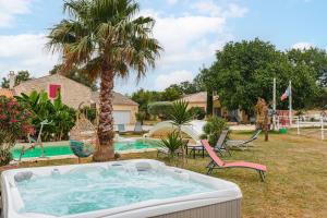 a hot tub in a yard with a palm tree at Roulotte la casetta Rita in Chambon