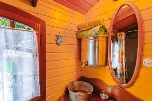 a yellow room with a mirror and a bucket at Roulotte la casetta Rita in Chambon