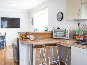 a kitchen with a counter with stools and a microwave at Chalet Skeabost Chalet by Interhome in Tole