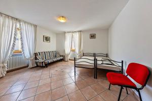 a room with a red chair and a bed and a couch at Appartamento Pisani in Brez