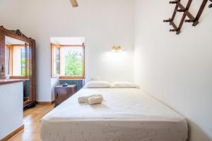 a white bedroom with a bed and a window at Ca'n Repic in Port de Soller