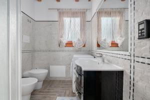 a white bathroom with a sink and a toilet at La finestra sul mare in Budoni +17 photos