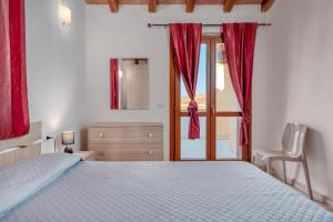 a bedroom with a bed with red curtains and a window at La finestra sul mare in Budoni