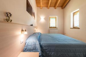 a bedroom with a blue bed and two windows at Nonno Bigi Genziana in Tremosine Sul Garda