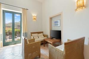 a living room with a television and a living room with a couch at Le Residenze In Piazza in Bosa