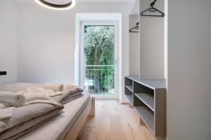 a white bedroom with a bed and a window at Haus Weinblick Apt 3 in Magrè allʼ Adige