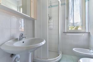 a white bathroom with a sink and a shower at Appartamento Trilo Fucini in Campo nell'Elba +16 photos