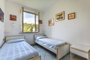 two beds in a room with a window at Appartamento Trilo Fucini in Campo nell'Elba