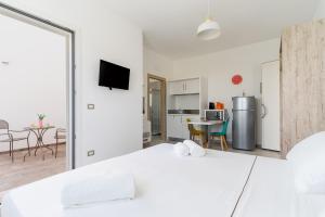 a white bedroom with a large bed and a kitchen at Le scuderie 9 in Galatone