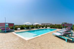 a swimming pool with chaise lounge chairs and a pool at Le scuderie 9 in Galatone