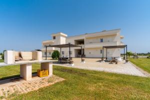a large white building with a patio and picnic tables at Le scuderie 9 in Galatone