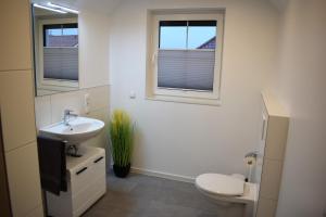a bathroom with a sink and a toilet and two windows at Ferienhaus Hanni in Geeste +6 photos