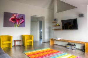 a living room with yellow chairs and a tv at Alpenblick 3 in Lindau-Bodolz