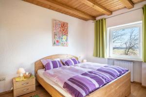a bedroom with a bed with purple sheets and a window at Das kleine Paradies in Pürgen