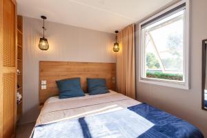 a bedroom with a bed with blue pillows and a window at Camping Lou Soulei 218 in Carry-le-Rouet +23 photos