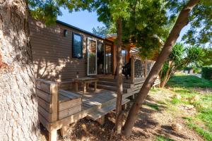 a cabin with a wooden deck next to a tree at Camping Lou Soulei 218 in Carry-le-Rouet
