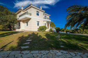 a large white house with a palm tree at Supreme and Classy Pool Residence in Paianía