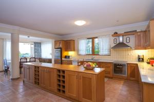 a kitchen with wooden cabinets and a bowl of fruit on the counter at Supreme and Classy Pool Residence in Paianía