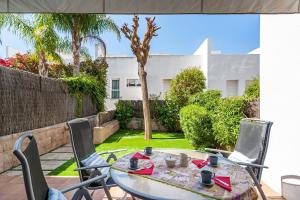 a table and chairs on a patio with a garden at Casa Alena in Conil de la Frontera