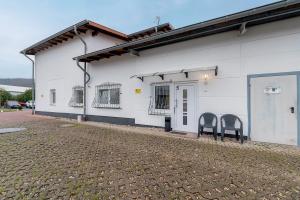 two chairs sit outside of a white building at 2 Bett Apartment a d A8 - W5 in Beckingen