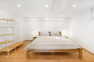 a white bedroom with a bed and two shelves at Ferienwohnung Apfelwiese in Meßstetten