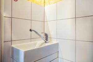 Ein weißes Waschbecken in einem Badezimmer mit weißen Fliesen in der Unterkunft Apartment Sonnengärtchen in Blankenburg