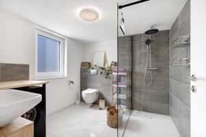 a bathroom with a shower and a toilet and a sink at Ferienwohnung Apfelwiese in Meßstetten +17 photos
