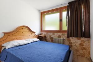 a bedroom with a blue bed and a window at Marilleva 900 Terminal in Mezzana